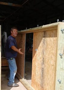 Madison's Homes contractor standing beside a custom-built 10-foot wooden window buck for a poured concrete basement foundation wall.