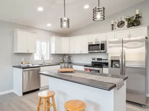 Kitchen remodeling project by Madison's Homes featuring white cabinets, center island, stainless steel appliances and updated lighting.