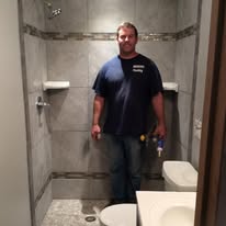 Gray tile walk-in shower with mosaic accents and built-in shelves, illustrating Madison's Homes tile shower services