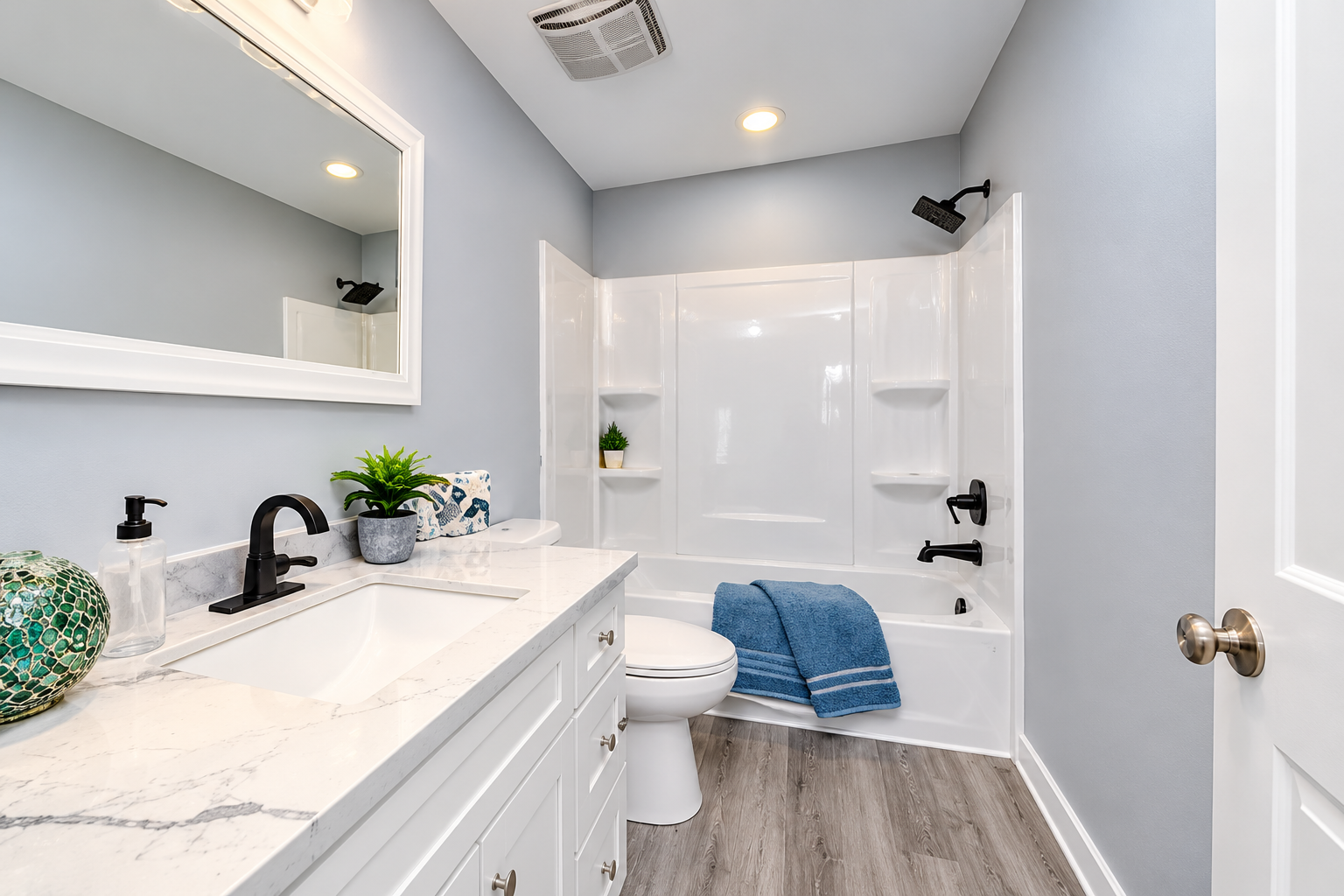 Modern bathroom with white bathtub and shower surround, black fixtures, white vanity, and gray flooring, illustrating bathtub and shower replacement services in Cedar Rapids and Marion, Iowa.