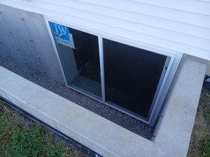 Finished basement window installed in poured concrete foundation with aluminum flashing and window tape by Madison's Homes in Linn County, Iowa